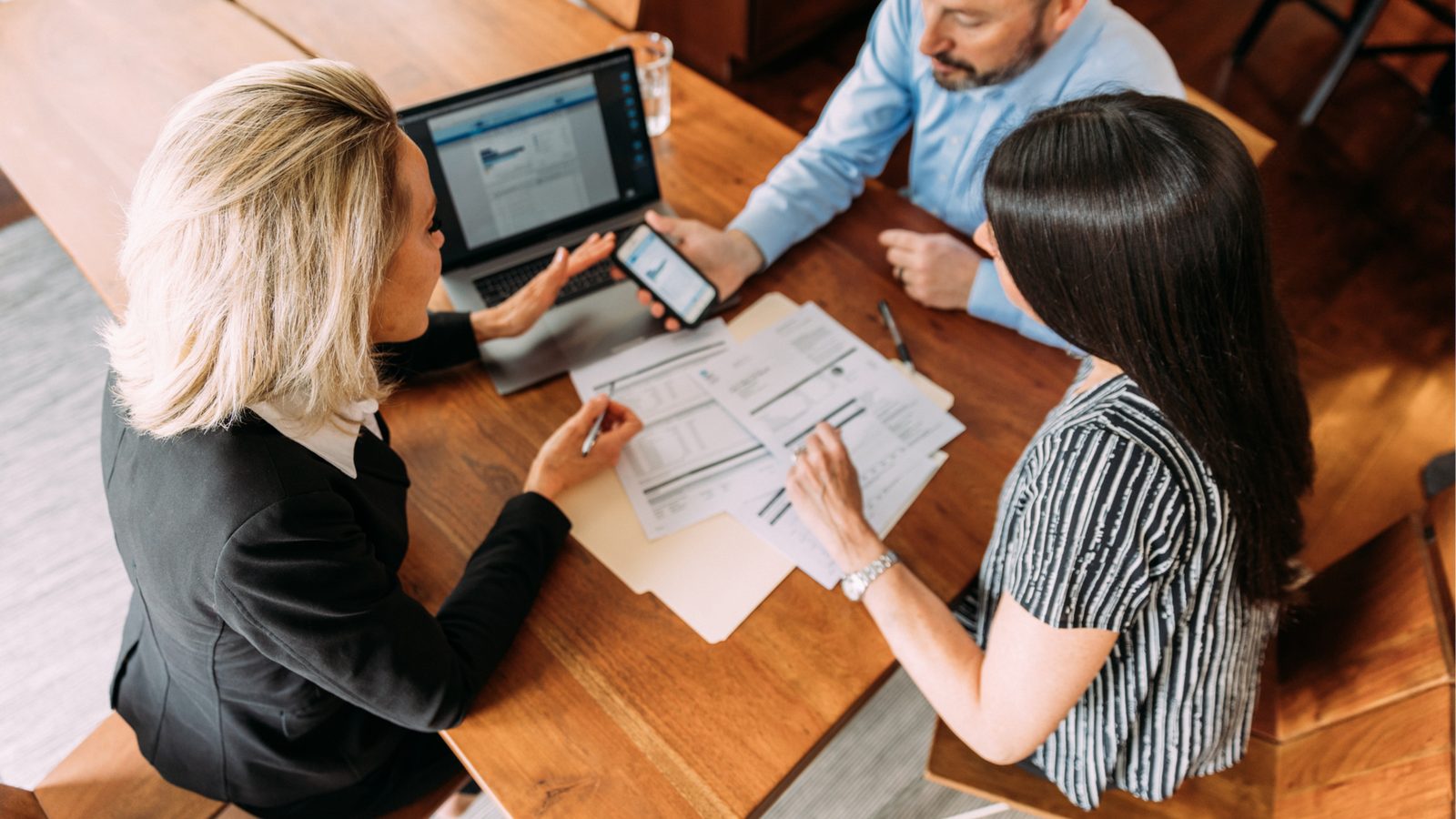 A financial advisor reviewing documents and portfolio figures with a couple during a client review meeting.