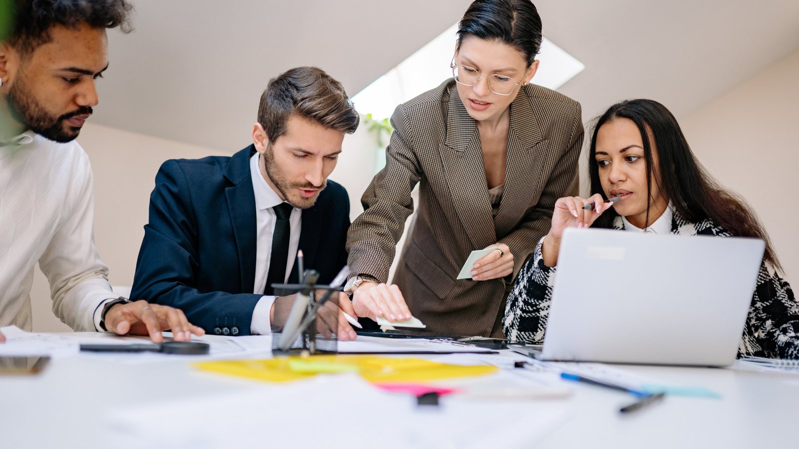 An advisory firm team reviewing documents and a laptop together at a shared desk.