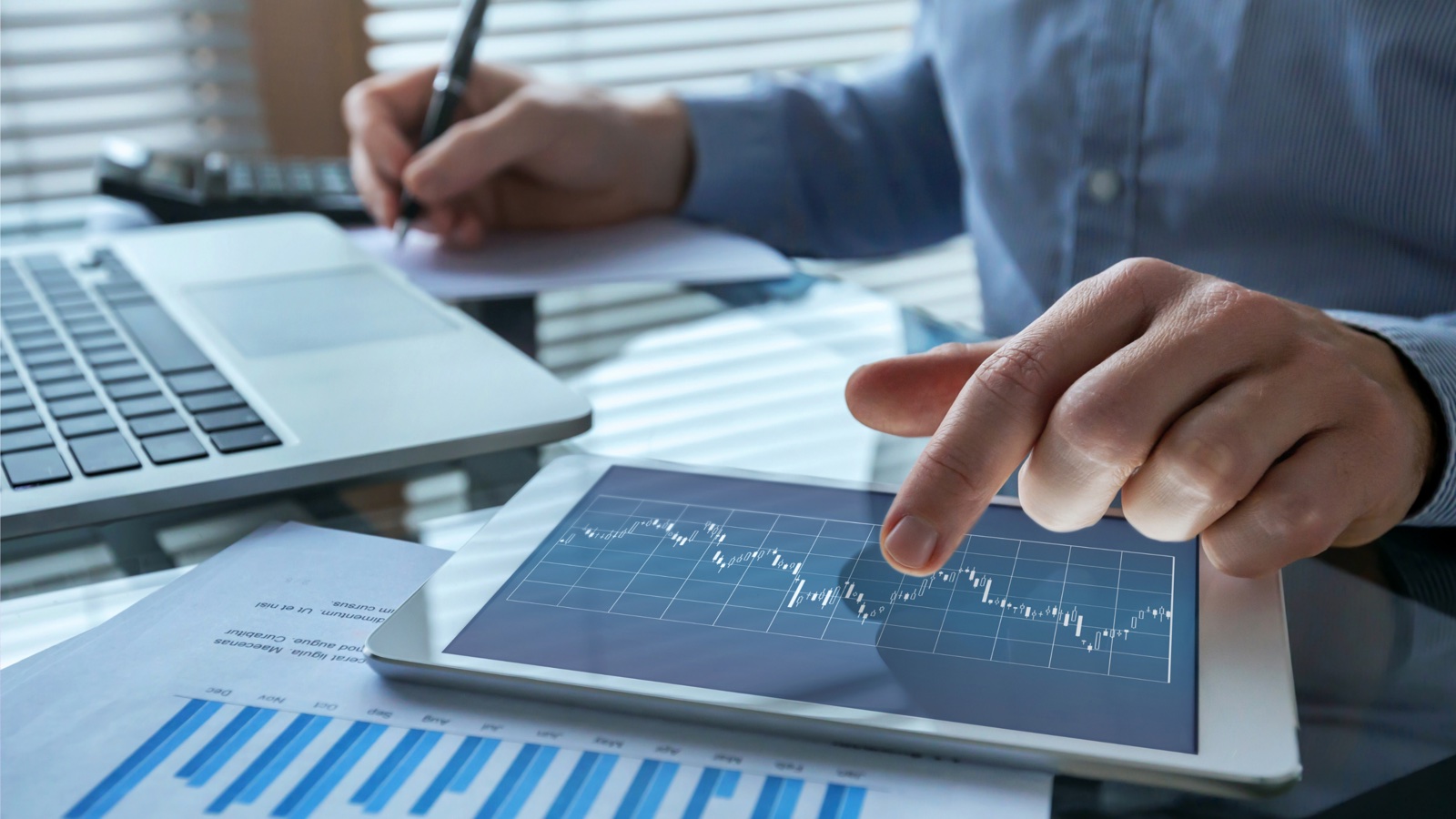 Advisor reviewing portfolio data across a laptop, tablet and printed report.